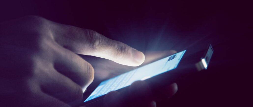 Hands holding and using smartphone in night light